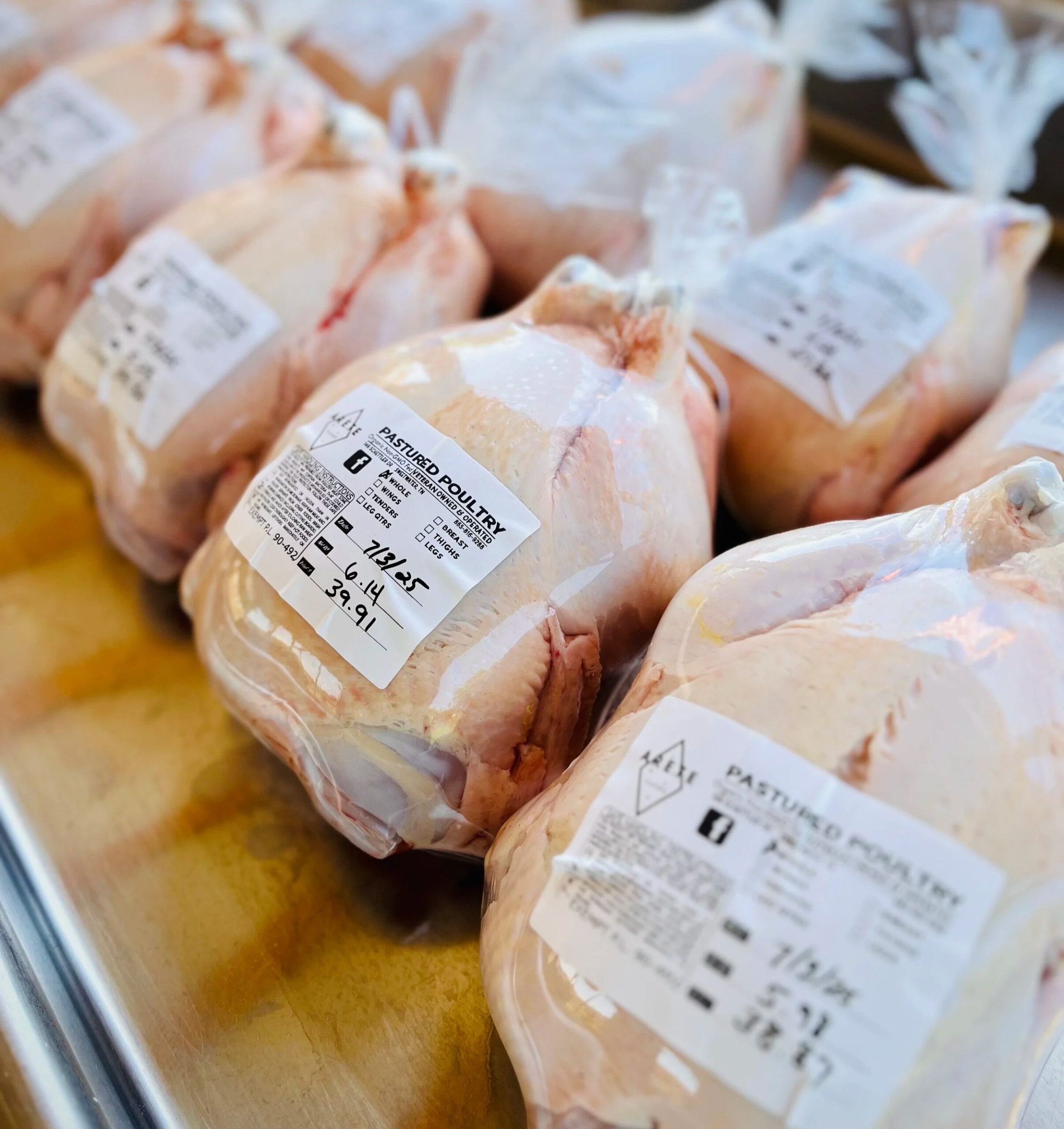 IMG_4709 Packaged pastured poultry ready for sale, displaying labels with pricing and product information. The image showcases multiple vacuum-sealed chicken products, emphasizing freshness and quality.